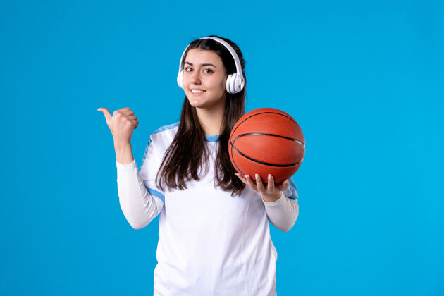 体育设备正面图微笑的年轻女性戴着耳机拿着篮球青少年持有女子