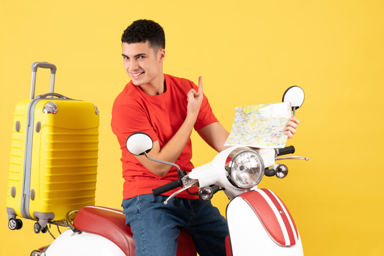 快乐的年轻人正面图：骑着轻便摩托车的快乐的年轻人拿着地图微笑人地图