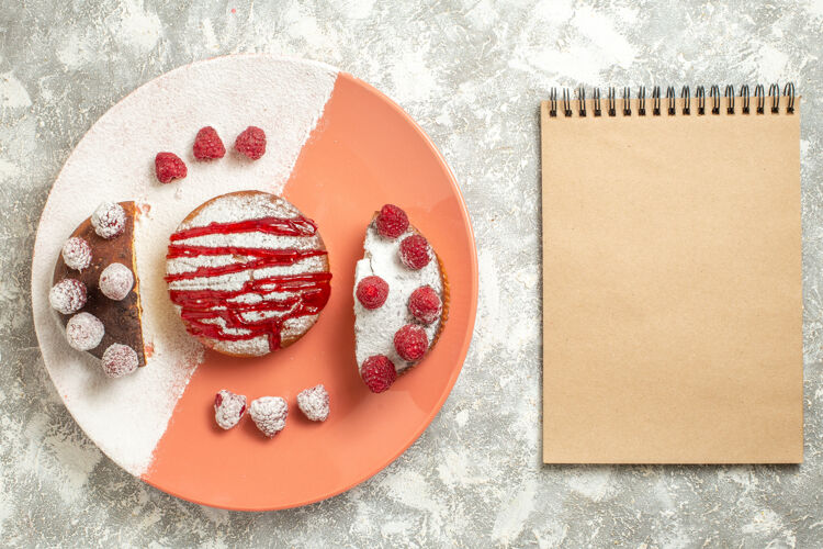 情人节甜点的顶视图 上面有酱汁和浆果 侧面有笔记本 背景是大理石壁板酱汁花
