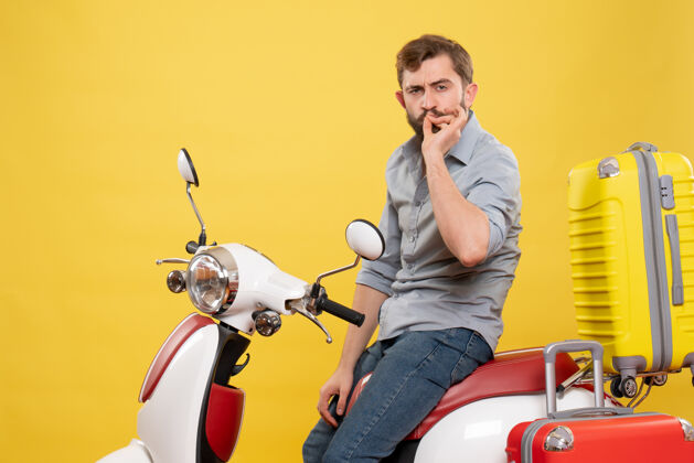 车旅游概念的正面视图 黄色的摩托车上坐着一个留着胡子的年轻人 手提箱在上面做着完美的手势制造自行车传送带