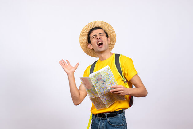 微笑正面图：一个穿着黄色t恤 头戴草帽的激动的年轻人拿着地图衬衫地图激动的年轻人