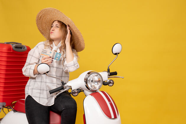 抱着忙碌的年轻女子戴着帽子 坐在摩托车上 拿着车票 听着黄色的最后一句闲话成人帽子八卦