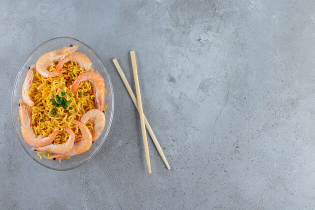 虾虾和面条放在玻璃盘上 旁边是筷子 背景是大理石料理中国菜拉面