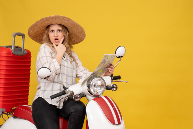年轻女子戴着帽子坐在摩托车上拿着地图的年轻女子的俯视图 脸上泛着困惑的忧郁人帽子高尔夫
