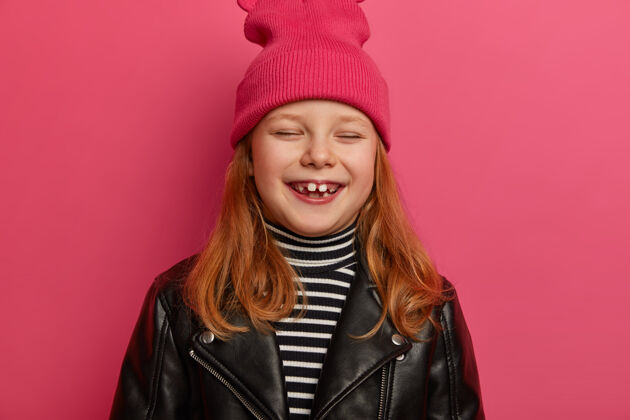 皮革漂亮的姜女头像有着俏皮乐观的表情 闭上眼睛开心地笑出来 有着积极的微笑 高兴地有了两颗成年的牙齿 去看牙医 隔离在粉红色的墙上微笑个人孩子