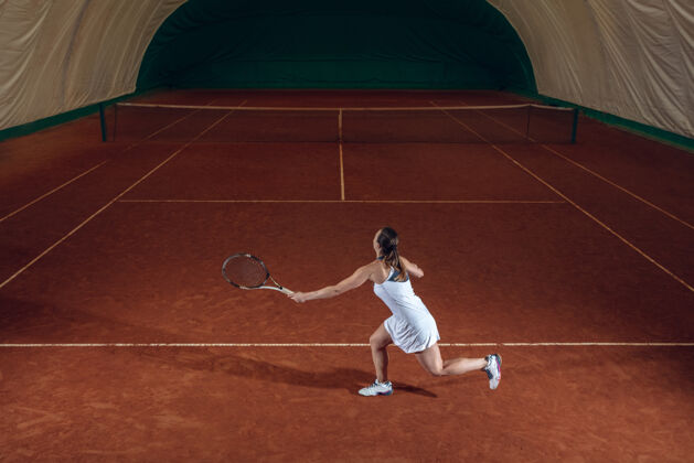 活动年轻的职业女运动员在运动场的墙上打网球广告体育场活跃