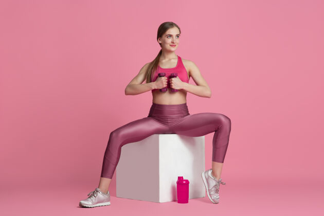 颜色美丽的年轻女运动员在粉红色墙上练习单色肖像女性单色强壮
