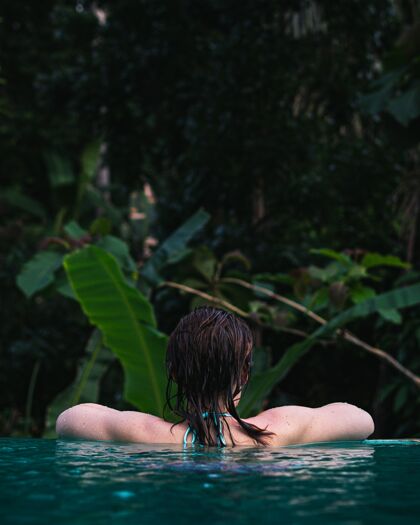 自然在水中游泳的女性背部的垂直镜头年轻水垂直