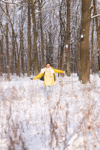 公园美丽的年轻开朗的女人在雪景的冬日森林里玩得很开心 穿着暖和的衣服在冬天和雪里快乐外面快乐美丽