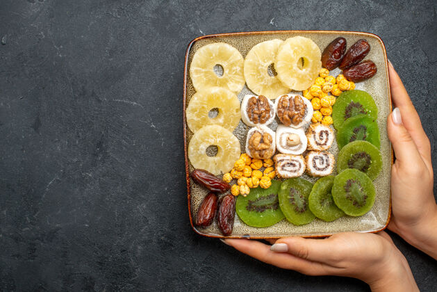 膳食顶视图切片干果菠萝环和猕猴桃与核桃在灰色办公桌上干果葡萄干甜维生素健康顶部水果视图