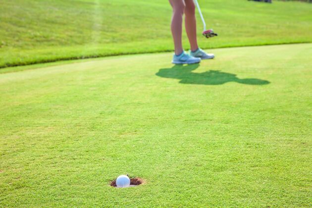 娱乐特写镜头的球进入一个洞在高尔夫球场与一名球员杯游戏草地