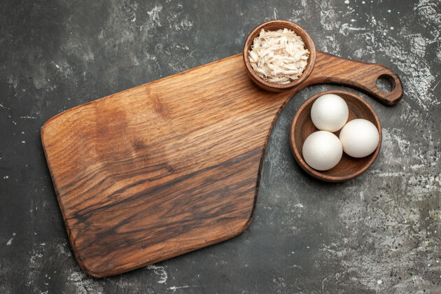 壳深灰色桌子上的盘子架顶视图 上面有奶酪碗 旁边有一碗鸡蛋烹饪球碗