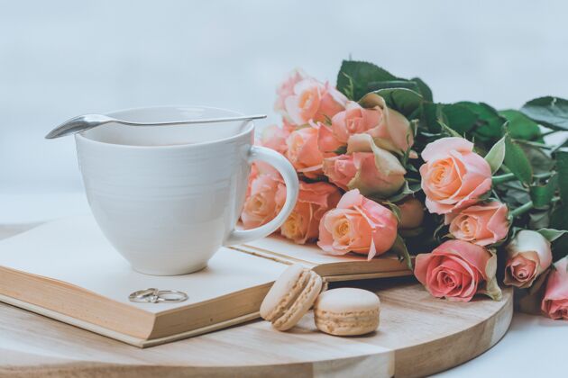 粉色一束粉红色的玫瑰放在木板上 上面放着一个玻璃杯和杏仁饼干浅色玫瑰浪漫