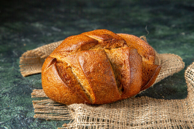 面包一条黑色膳食面包的俯视图 棕色毛巾 深色表面 有自由空间视野毛巾面包皮