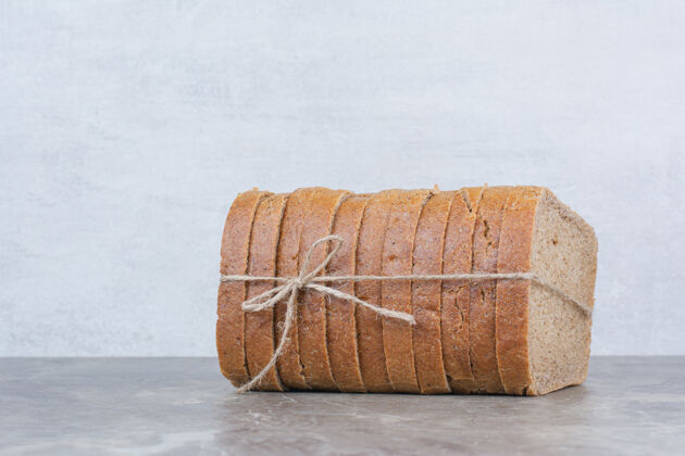 面包用绳子把棕色面包片放在大理石表面面包切健康