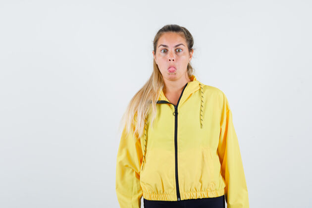 健康穿着黄色雨衣的年轻女人伸出舌头 看起来很奇怪人舌头光