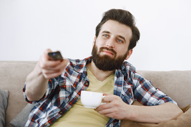 杯子男人喝咖啡 男人在沙发上看电视 手里拿着电视遥控器电视可爱男人