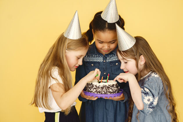 食物孩子们的生日被隔离在黄色的墙上孩子们拿着蛋糕庆祝混合微笑
