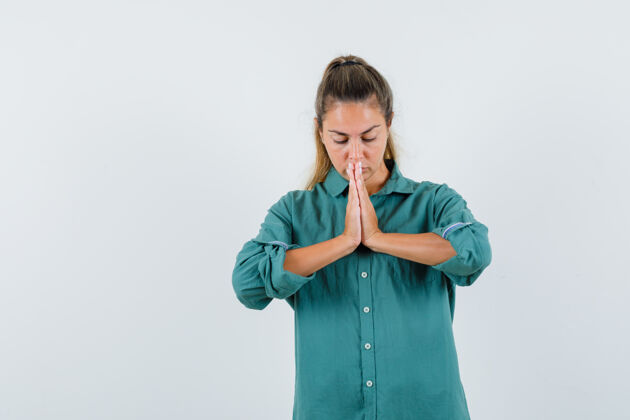 年轻一个穿着蓝色衬衫 神情专注的年轻女人在祈祷快乐人手