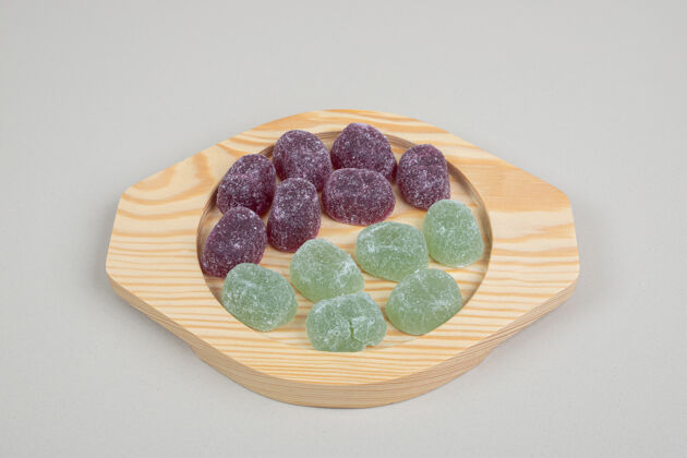 切片绿色和紫色的果冻糖果放在木盘上邦邦五颜六色零食