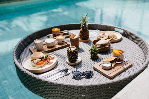 桌子太阳镜 汉堡包和果汁游泳池提供异国风味的午餐甜点泳池边午餐