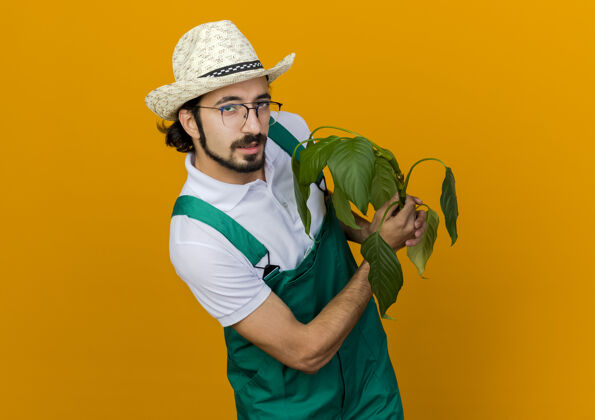 男自信的男园丁戴着眼镜戴着园艺帽捧着植物花园信心园艺