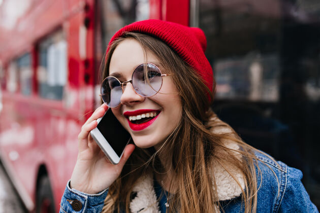年轻一个戴着红帽子的年轻女子在街上打电话的特写镜头欢呼电话女性
