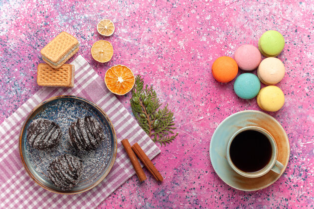 饼干俯瞰美味的巧克力蛋糕与一杯茶和法国马卡龙粉红食物杏仁饼美味