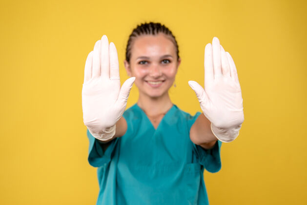 健康浅黄色墙上戴着特殊手套的女医生的正视图护士病毒光