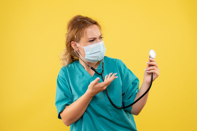 健康黄墙上穿着医疗服 戴着听诊器面罩的女医生的正视图大流行实验服医疗