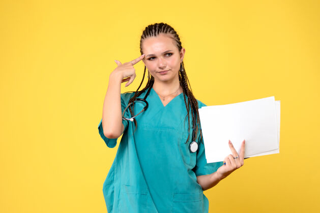 女医生身着医疗服的女医生的正面图 黄色的墙上有纸漂亮疾病医院