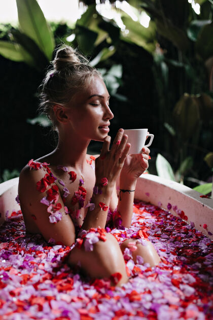 水疗时尚发型的女人在浴室里摆姿势 端着一杯茶迷人的欧洲女人在周末享受水疗 喝着咖啡自然女人浴室