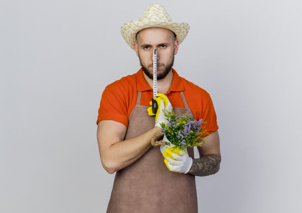 男自信的男园丁戴着园艺帽拿着卷尺和花盆帽子测量花盆
