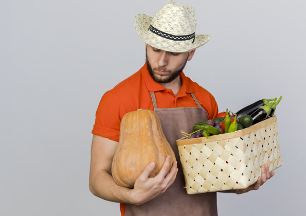 持有自信的男园丁戴着园艺帽 手里拿着菜篮子 看着南瓜穿花园篮子