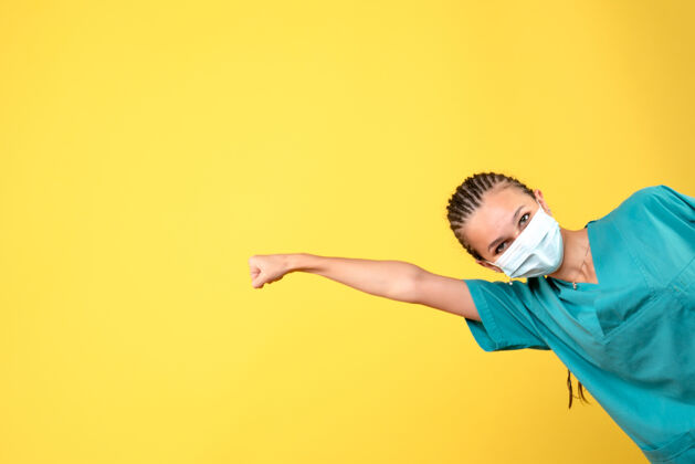 黄色正面图：穿着医用衬衫和面罩的女医生 大流行卫生医院的彩色护士颜色复制空间面具