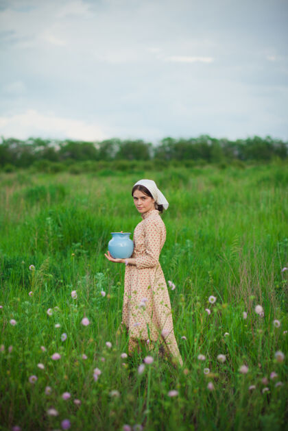 成人那个戴着围巾拿着苹果的女人对着绿色的草地乡村家庭乡村
