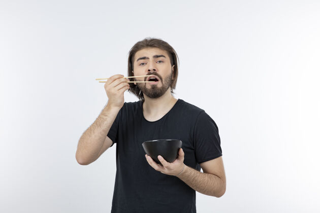人一个留胡子的男人拿着筷子在白色的墙上拿着碗小伙子摆姿势男性