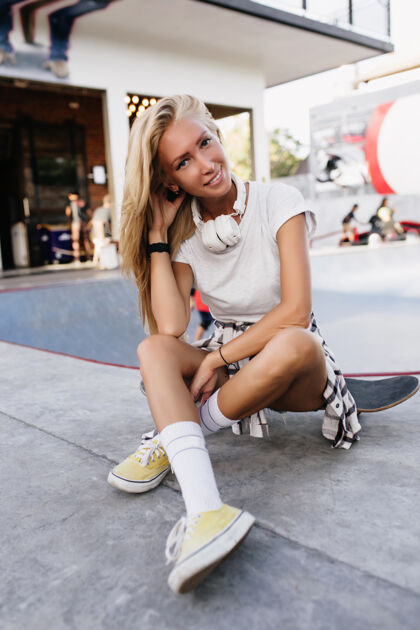 街道穿着白色t恤的性感白种女人坐在长板上无忧无虑的金发女郎在溜冰场玩头发的户外照片女性城市活动