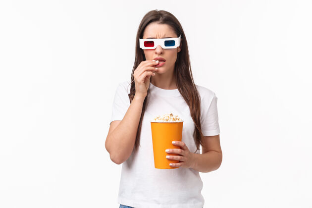 欢乐一个吃着爆米花 戴着3d眼镜的年轻女人人物年轻肖像