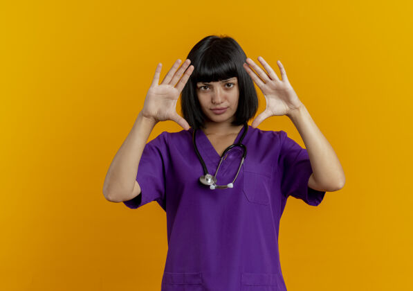 制服自信的年轻黑发女医生穿着制服 手持听诊器 举手示意空间医生手