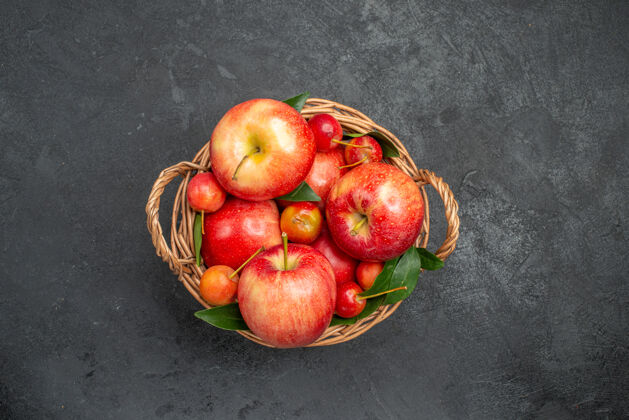 水果从远处俯瞰深色桌子上放着樱桃和苹果的果篮苹果樱桃深色