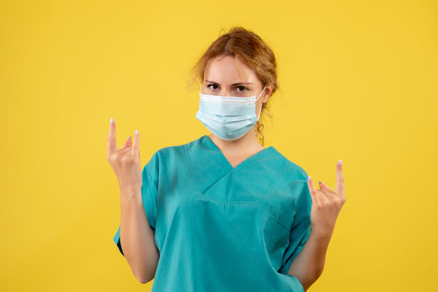 正面黄墙上年轻女医生穿着医疗服 戴着口罩的正面图年轻女医生健康人