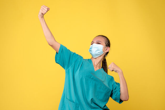 绝育黄墙上穿着医疗服 戴着无菌口罩的女医生的正面图医疗套装面具