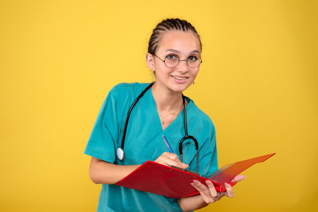 衬衫穿着医用衬衫的女医生在黄色墙上写笔记的正面图医疗器械健康书写