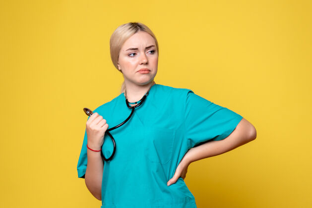 衬衫黄色墙壁上穿着带听诊器的医用衬衫的女医生的正视图人前面听诊器