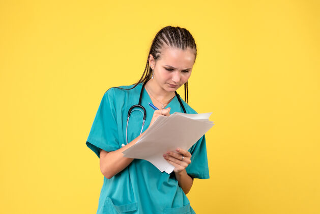纸张身着医疗服的女医生的正面图 黄色的墙上有纸疾病情绪前面