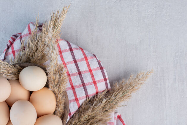 配料鸡蛋和羽毛草梗放在一个碗里 放在大理石桌上的毛巾上农产品早餐贝壳