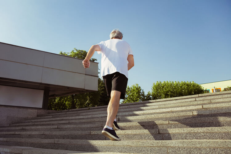跑步在城市街道上戴着臂章或健身的高级男子跑步者高加索男模在夏天的早晨练习慢跑和有氧训练健康的生活方式 运动 活动理念自然训练健身