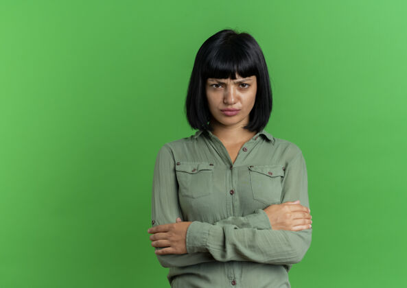背景年轻的黑发白人妇女站着 双臂交叉 在绿色的背景上与复制空间隔离黑发交叉手臂