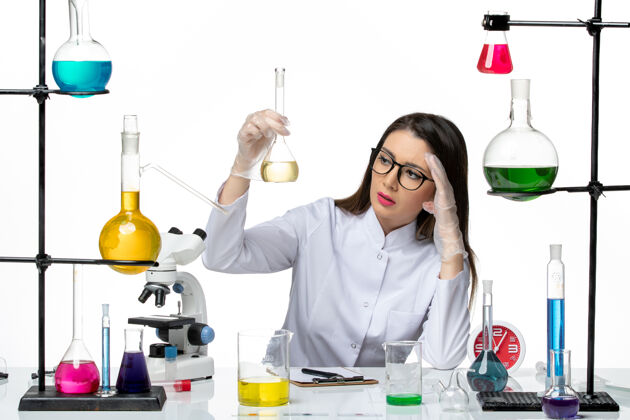 正面前视图穿着白色医疗服的女化学家拿着白色背景上的溶液-科学大流行实验室病毒西装举行实验室